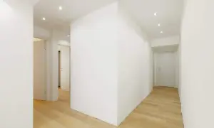 Corridoio moderno con pavimenti in legno e muretti divisori in cartongesso che creano un gioco di volumi.