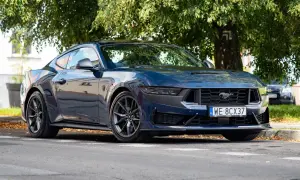 Nowy Ford Mustang 2025 w ciemnoniebieskim kolorze, zaparkowany pod drzewem.