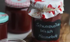 Glas mit hausgemachter Kirschmarmelade, beschriftet mit "Schwarzwälder Kirsch Marmelade". Ein tolles Rezept für den Sommer!