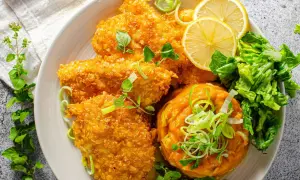 Knuspriges Zucchin Schnitzel mit Kürbispüree, Salat und Zitronenspalten.
