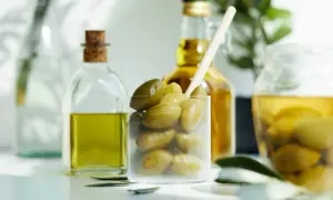 Zielone oliwki w szklance i butelkach z oliwą. Czy oliwa z oliwek jest kaloryczna? Tak, jest, ale zdrowa!