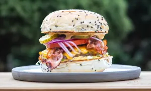 Apetyczny burger z bekonem, serem i warzywami na talerzu.