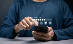 Osoba korzysta z telefonu, na którym widać pasek postępu "UPDATING... 70%" i ikony związane z aktualizacjami systemu Android.