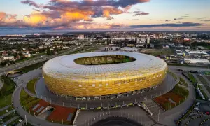 Stadion Energa w Gdańsku, znany jako Letnica Gdańsk, lśni złotem pod zachodzącym słońcem.