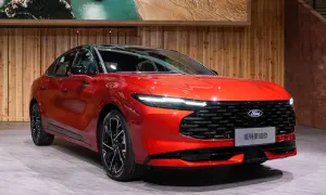 Nowy, lśniący, czerwony Ford Mondeo MK6 prezentuje się na tle drewnianej ściany i obrazu z krajobrazem.