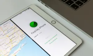 Tablet z mapą i aplikacją "Find My iPhone" do lokalizacji telefonu. Obok klawiatura laptopa.