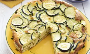 Une délicieuse frittata courgette, garnie de rondelles de courgettes fraîches et dorées, servie sur une assiette jaune.