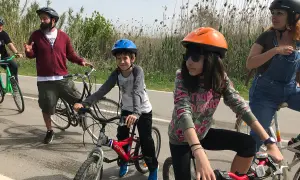 Familia disfrutando de rutas en bici con niños en Cataluña. Niños y adultos con cascos, listos para pedalear en un día soleado.