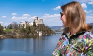 Widok na zamek nad jeziorem, z kobietą w kolorowej kurtce na pierwszym planie. To wspaniałe niedzica atrakcje turystyczne.