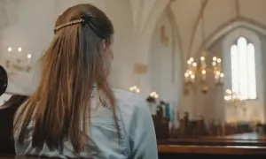 Młoda kobieta w kościele, rozważająca przyczyny utraty wiary u młodzieży. Wyniki badań socjologicznych 2026.