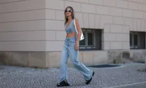 Modna kobieta w jeansach bootcut i denimowym topie, z białym przezroczystym plecakiem. Stylowe jeansy bootcut stylizacje.