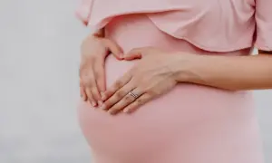 Gravid mage i vecka 21, en hand formar ett hjärta på magen.