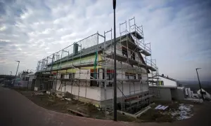 Haus im Bau mit Gerüst und Dämmung unter bewölktem Himmel.