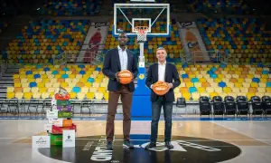 Dos hombres posan con balones de baloncesto en una cancha vacía. Detrás de ellos, una pila de cajas de frutas y asientos de colores. Un guiño al club baloncesto Gran Canaria.