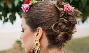 Peinado recogido con flores, estilo flor flamenca pelo suelto, luciendo un gran pendiente dorado.