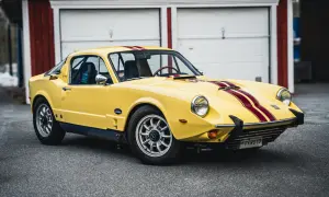 Gul Saab Sonett 2 med röda ränder, parkerad framför ett rött garage.