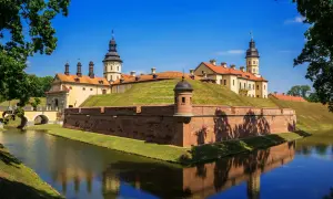 Zamek Mir, jedna z głównych atrakcji Białorusi, otoczony fosą i ceglanymi murami obronnymi, odbija się w spokojnej wodzie.