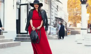 Kobieta w czerwonej sukni i czarnej ramonesce prezentuje stylowe stylizacje dla grubych nóg. Czarny kapelusz dodaje elegancji.