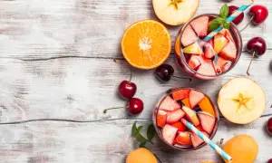 Sangria ricetta bar: bicchieri pieni di frutta fresca, arancia, mele, ciliegie e albicocche su un tavolo di legno.