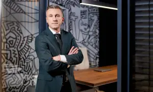 Mężczyzna w garniturze stoi z rękami skrzyżowanymi na piersi w nowoczesnym biurze.