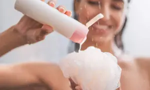 Mujer sonriente aplica shower cream para que sirve: limpieza e hidratación para una piel suave y radiante.