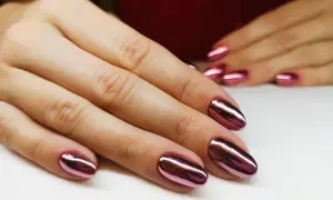 Dłonie z błyszczącym, metalicznym różowym manicure tytanowym. Czy ten efektowny manicure tytanowy rakotwórczy jest wart ryzyka?