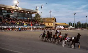 Corsa di cavalli al trotto all'ippodromo Montegiorgio, con pubblico sugli spalti e cavalli in azione sulla pista.