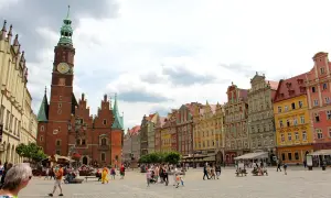Buntes Treiben auf dem Marktplatz der Breslau Innenstadt. Das Rathaus mit seinem markanten Turm dominiert die Szene, umgeben von farbenfrohen Bürgerhäusern.