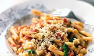 En skål med strozzapreti pasta, toppad med riven ost och en gaffel redo att hugga in.