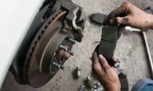 Mechanik trzyma zużyte klocki hamulcowe. Sprawdź wymiana klocków hamulcowych cena i zadbaj o bezpieczeństwo.