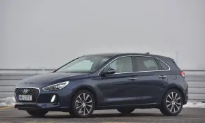 Ciemnoniebieski Hyundai i30 na parkingu. Kierowca w okularach siedzi za kierownicą, gotowy do wymiany żarówki.