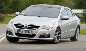 Srebrny Volkswagen Passat CC z czarnym dachem sunie po drodze.