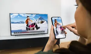 Klonowanie ekranu: rodzina ogląda film z sankami na telewizorze i smartfonie.