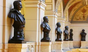 Büsten von Männern im Nationalmuseum Prag, flankiert von Säulen und einer reich verzierten Decke.