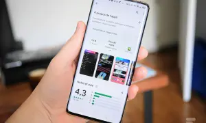 Main tenant un smartphone Samsung, affichant la page d'une application sur le Play Store, prêt à mettre à jour une application.