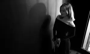 Eine Frau in einem eleganten, schulterfreien Kleid wartet im Schatten. Perfekt für einen Anlass mit "black tie optional"-Dresscode.