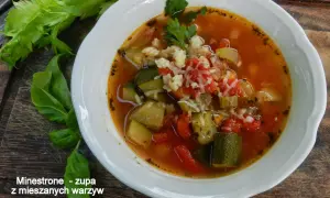 Miseczka zupy minestrone z warzywami i startym serem, obok łodygi selera i liście bazylii.