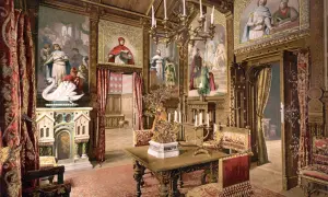 Prunkvoller Salon im Schloss Neuschwanstein innen. Wandmalereien mit Sagenmotiven, ein Kamin mit Schwan, prunkvolle Möbel und ein Kronleuchter schaffen königliches Ambiente.