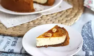 Tranche de cheesecake ricotta onctueux, garnie de noisettes caramélisées. Un délice gourmand.
