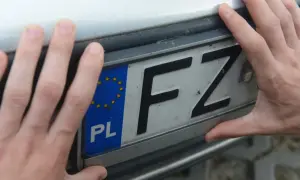 Dwie dłonie trzymają polską tablicę rejestracyjną z literami FZ.