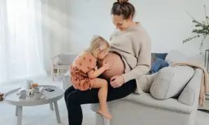 Liten flicka kramar sin mammas mage. En fin stund för en gravid kvinna som tar folsyra.