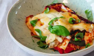 Ein Stück köstliche vegetarische Lasagne mit geschmolzenem Käse und frischem Basilikum in einer Schüssel.