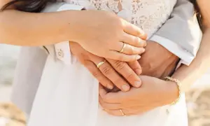 Manos entrelazadas con anillos de boda, mostrando dónde se pone el anillo de compromiso. Un detalle de amor eterno.