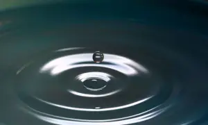 Kropla wody zawieszona w powietrzu, tworząca idealne kręgi na powierzchni. Jakby zatrzymany kadr z filmu łzowego, pełen emocji i refleksji.