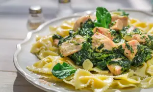 Pyszna sałatka ze szpinakiem i makaronem farfalle z kawałkami kurczaka w kremowym sosie.