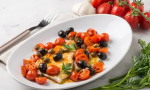 Piatto di pesce spada con pomodorini, olive nere e capperi. Una ricetta mediterranea gustosa e colorata.