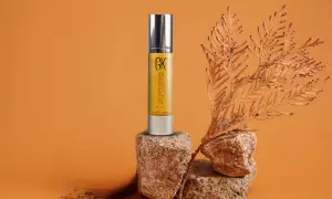 Sérum capilar GK Hair en envase dorado, con ramas secas y rocas. Descubre las maravillosas aceite de argan propiedades para tu cabello.