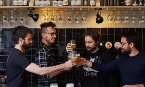 Amici brindano durante una visita birrificio. Bottiglie di birra e bicchieri in primo piano.