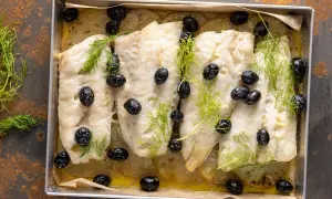 Merluzzo al forno con patate, olive nere e finocchietto fresco. Un piatto semplice e gustoso, pronto per essere servito.