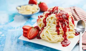 Ein köstliches Spaghetti-Eis-Dessert mit Erdbeersauce und frischen Erdbeeren.